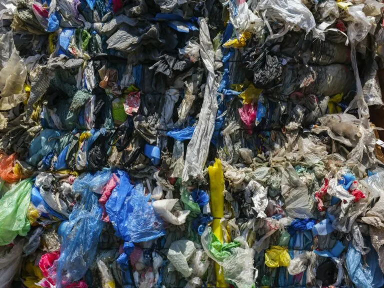 Primer plano de desechos plásticos compactados, listos para reciclaje industrial y procesamiento. Contribuye a la economía circular.
